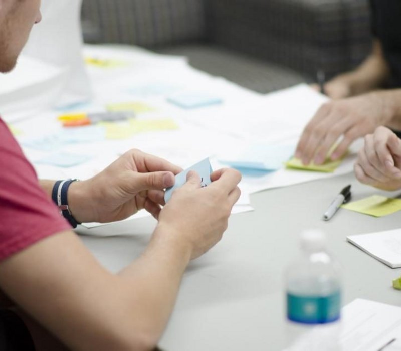 Atelier citoyen autour d’une table, post-it et plans
